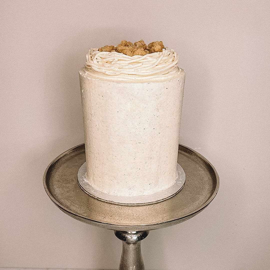 A tall cream celebration cake with a textured top by Khoya