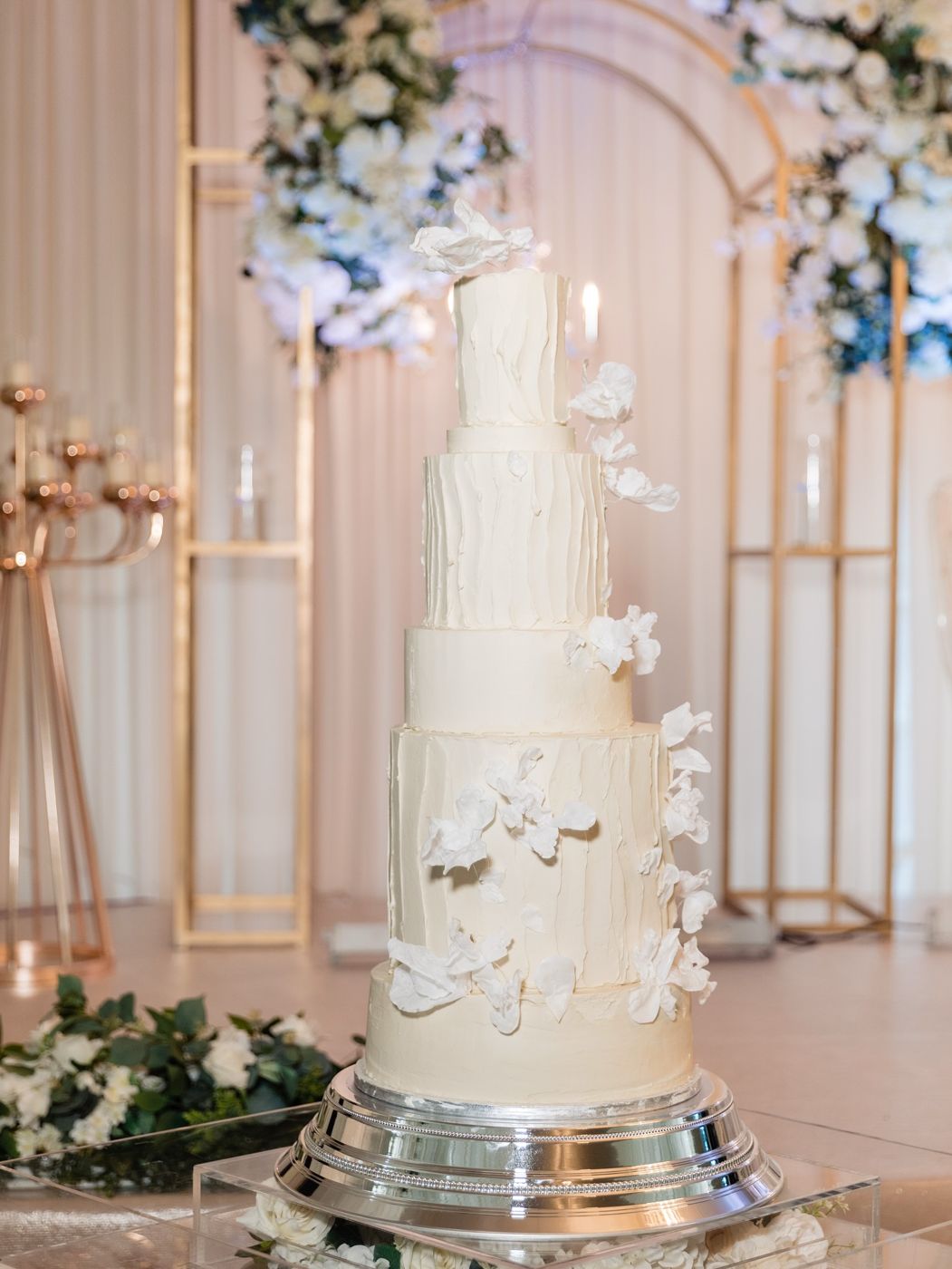 A tall white wedding cake dressed with delicate flowers